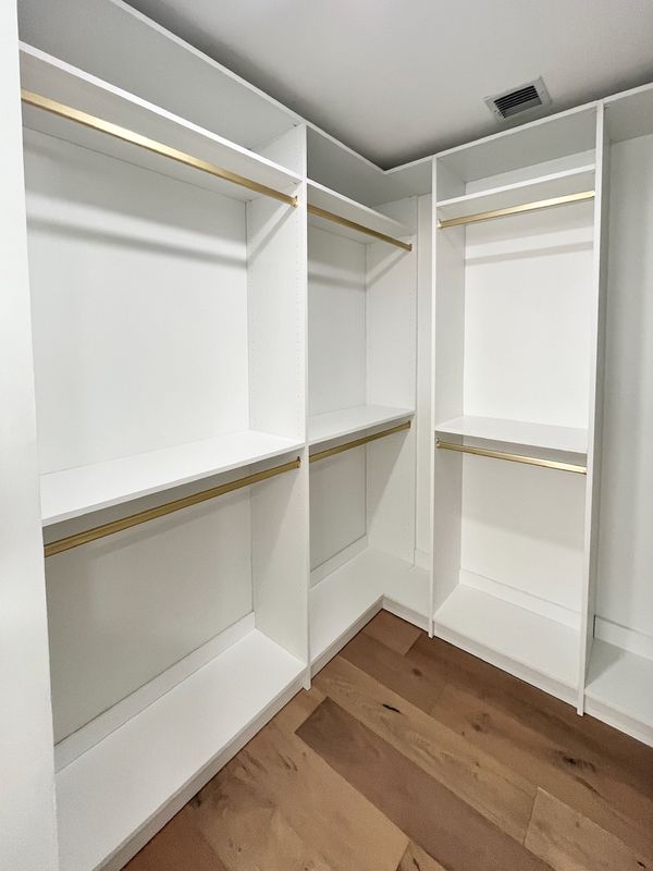 White closet with gold hanging rods