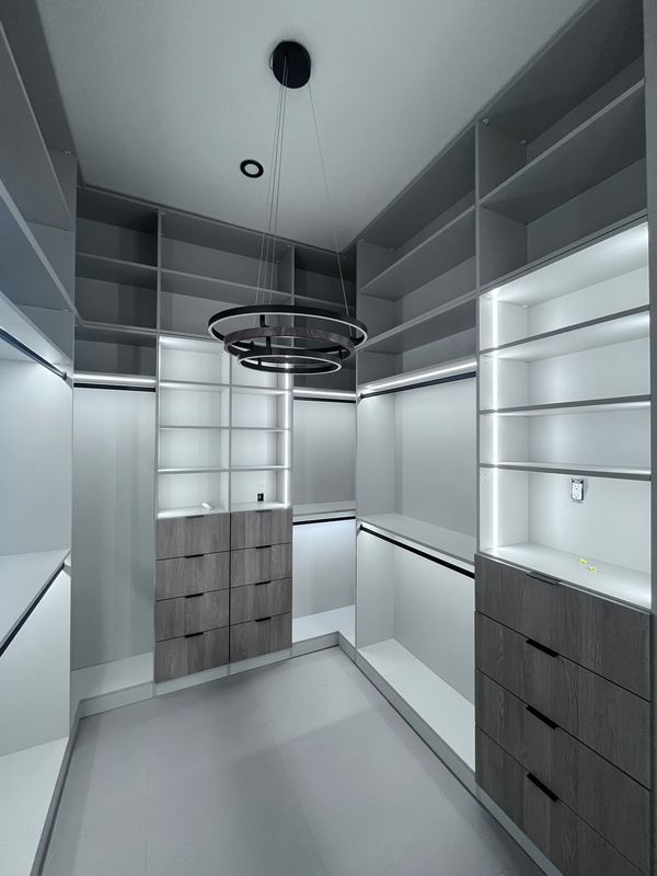 Lit walk-in closet with grey wood drawers