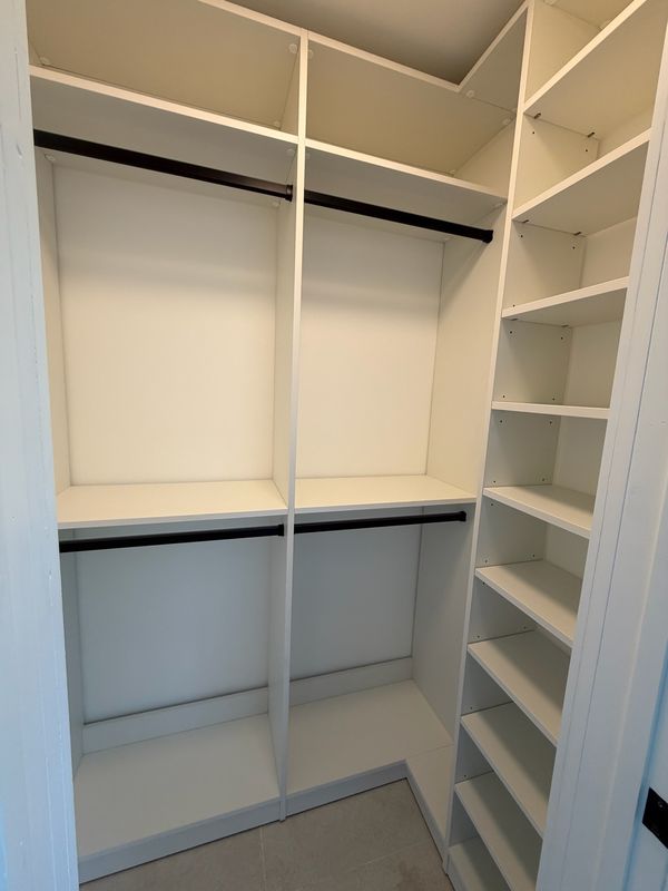 White corner walk-in closet with black rods